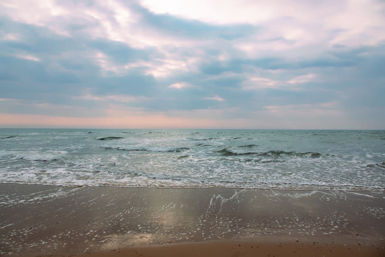 Calm coastal horizon under a soft cloudy sky