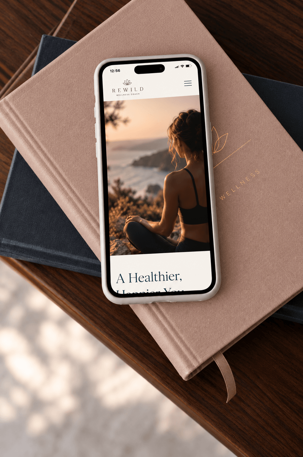 Phone showing a wellness coach website, resting on a stack of books