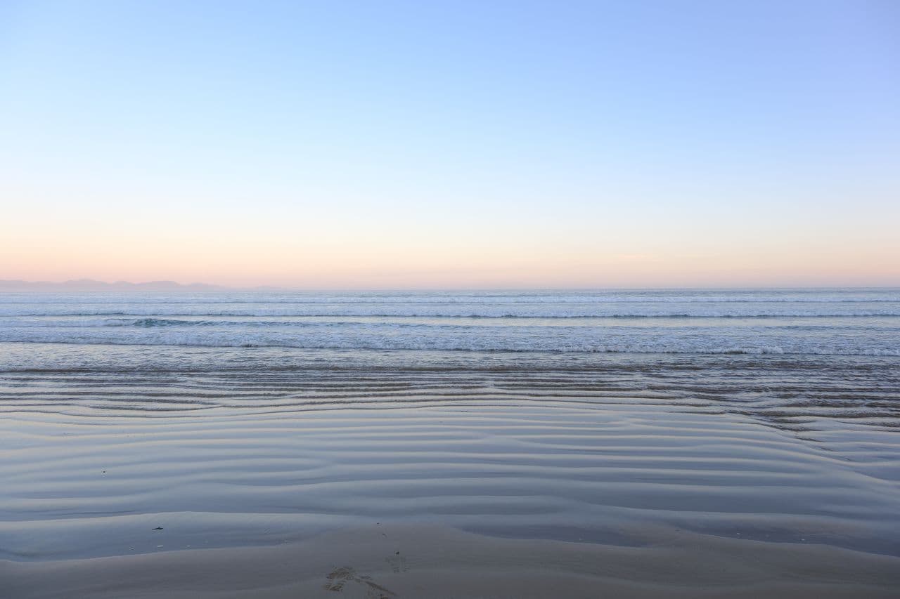 Soft coastal horizon at dusk over rippled sand